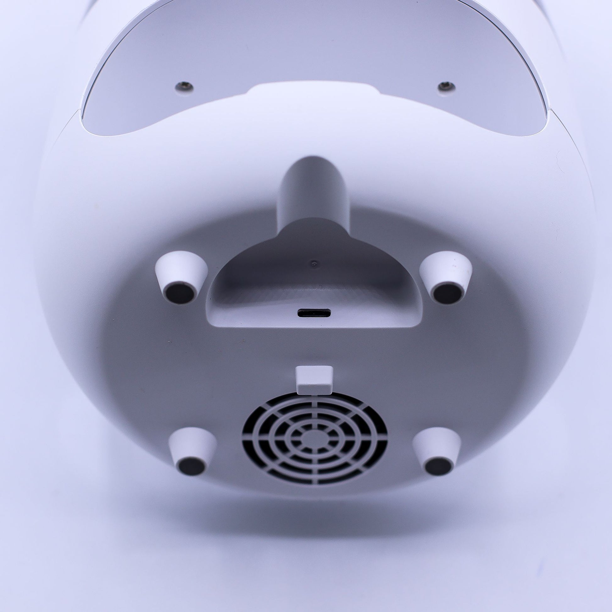 Base blanca de difusor con puerto USB-C, cuatro patas antideslizantes y rejilla de ventilación circular.