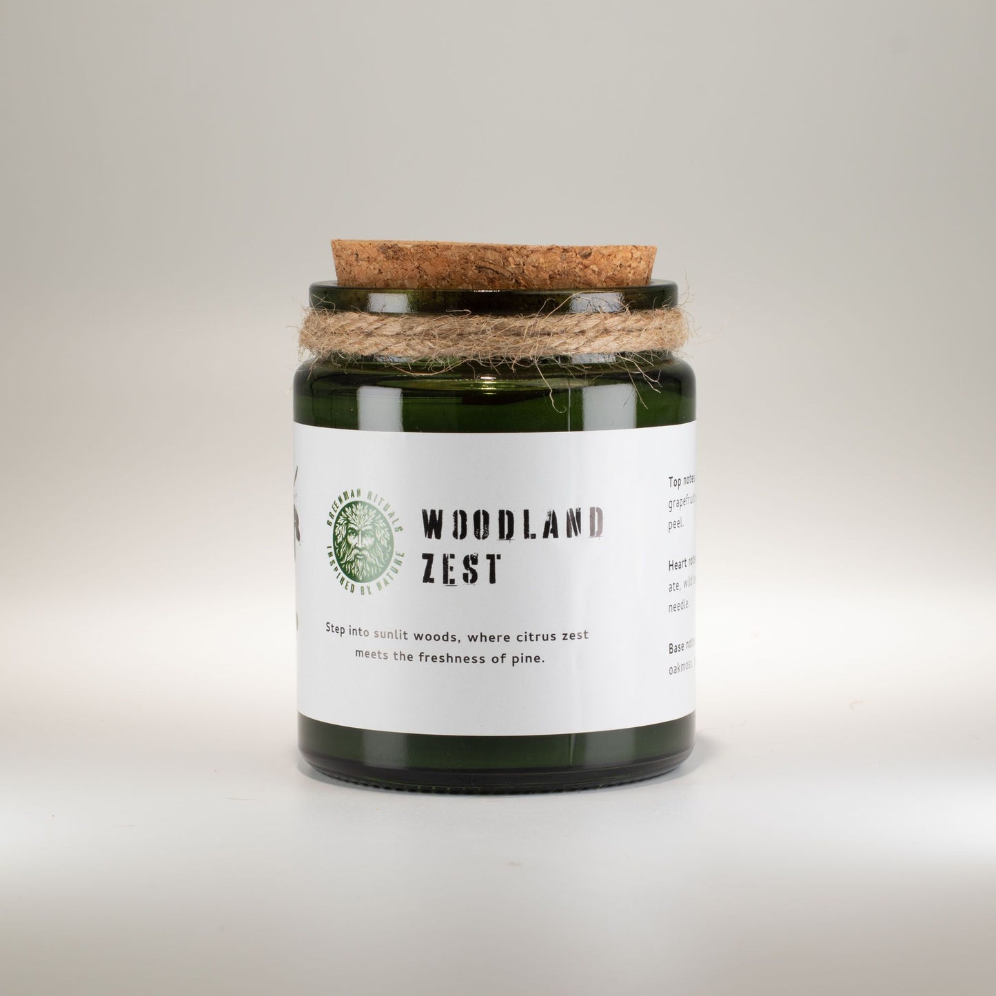 Vela verde "Woodland Zest" en recipiente de vidrio, con tapa de corcho y cuerda decorativa, aroma a cítricos y pino.