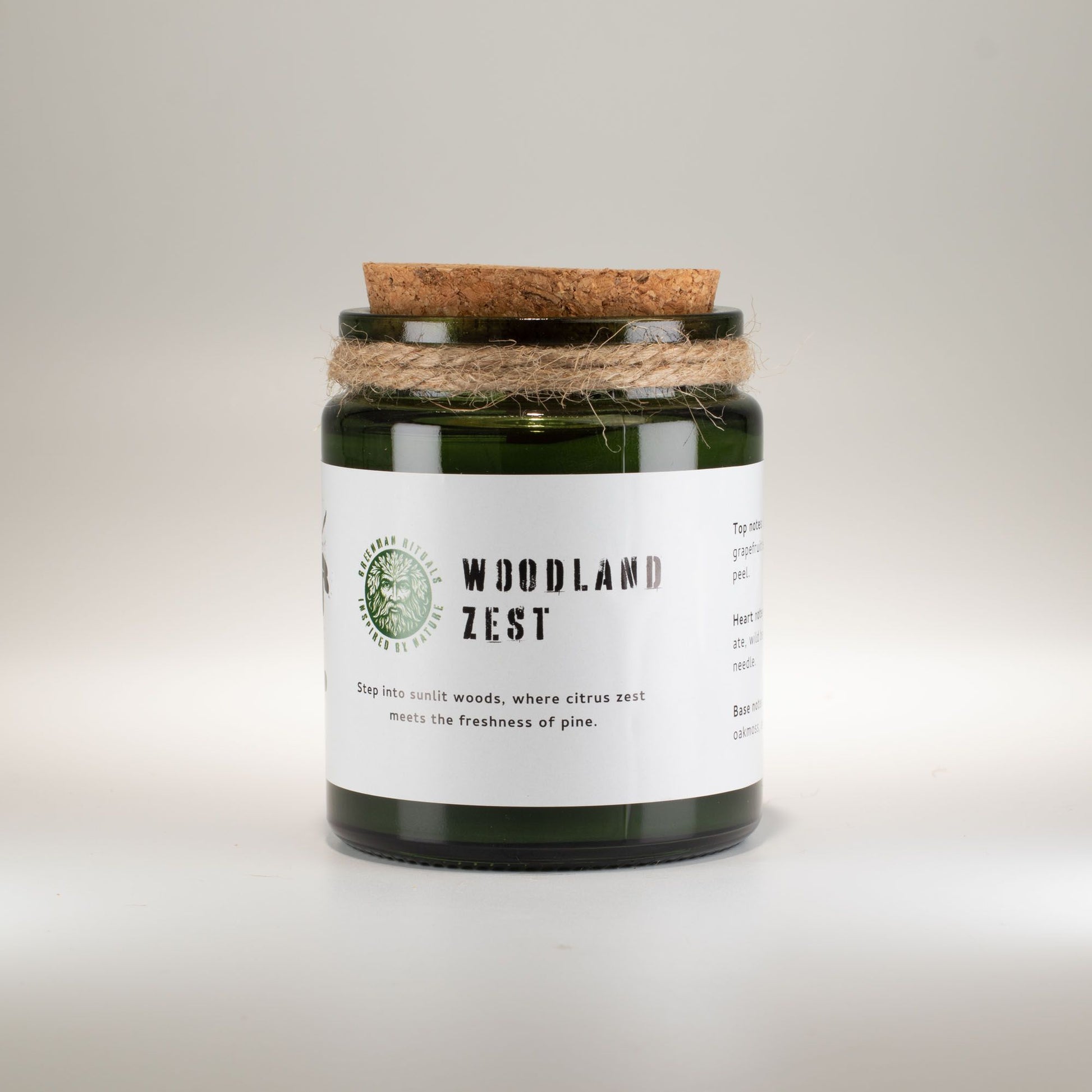 Vela verde "Woodland Zest" en recipiente de vidrio, con tapa de corcho y cuerda decorativa, aroma a cítricos y pino.
