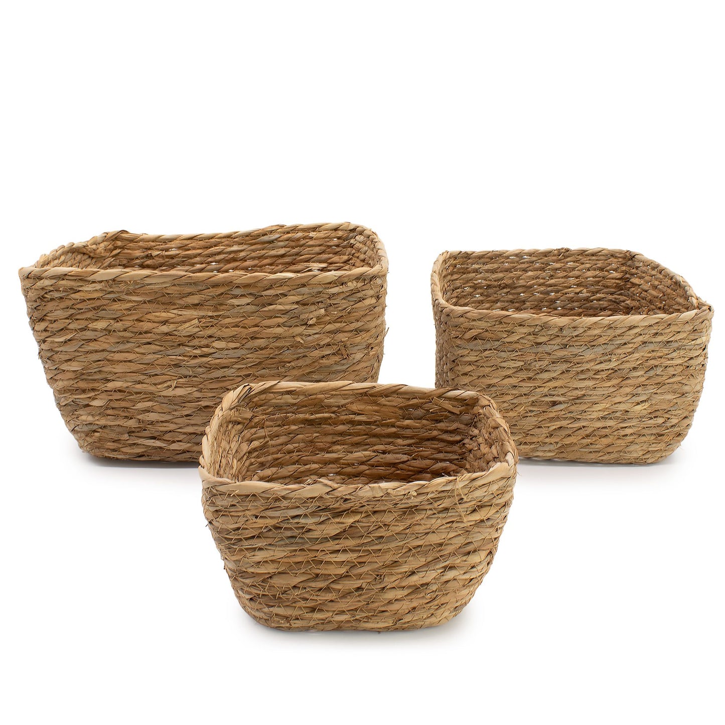 Juego de tres cestas cuadradas de fibras naturales de hierba marina y hoja de plátano en tono beige sobre fondo blanco.