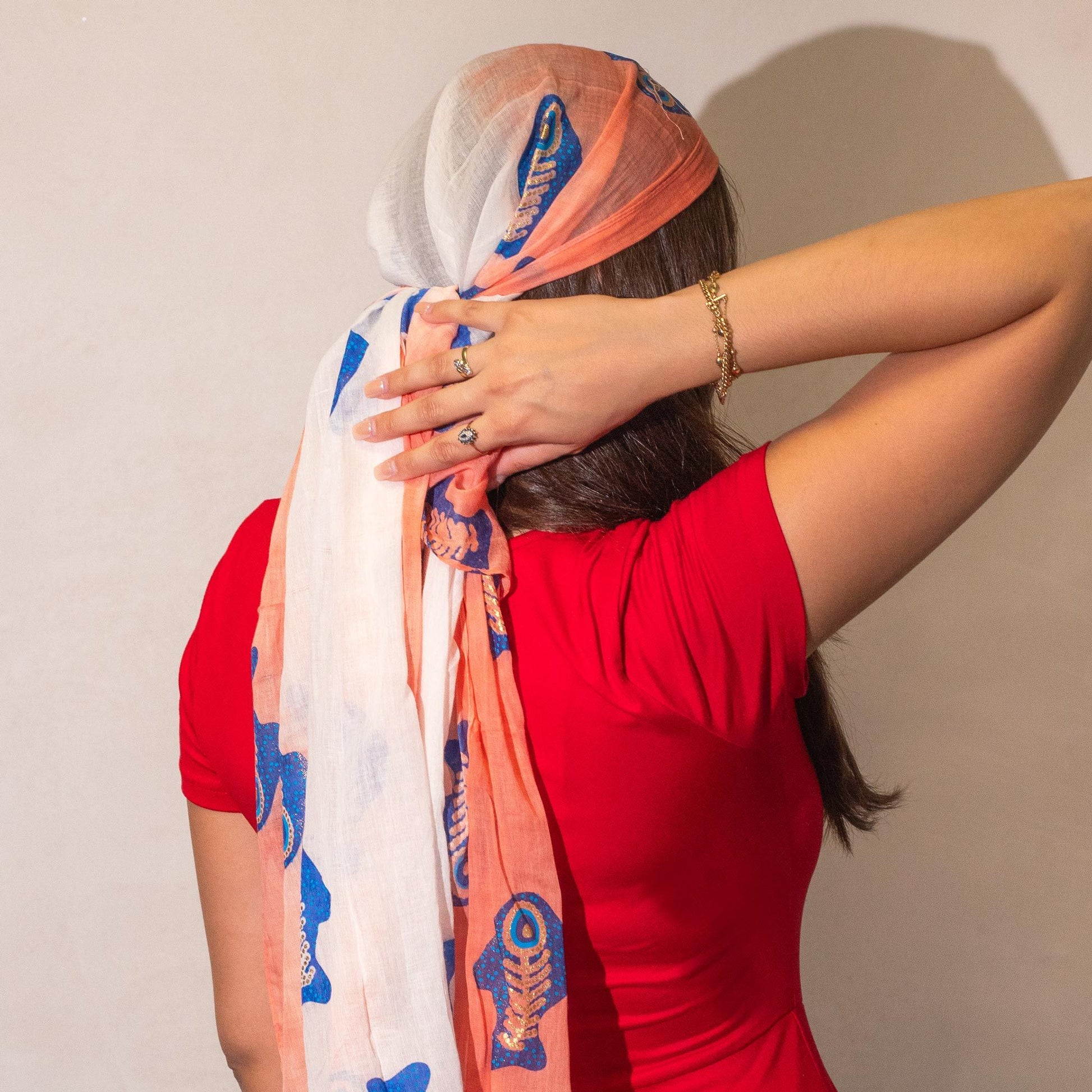 Pañuelo de seda blanco y coral con estampado azul de peces, estilo boho, ideal para complementar tu outfit.