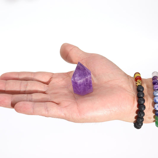 Cristal de amatista púrpura en forma de pico, sostenido en una mano masculina, fondo blanco.