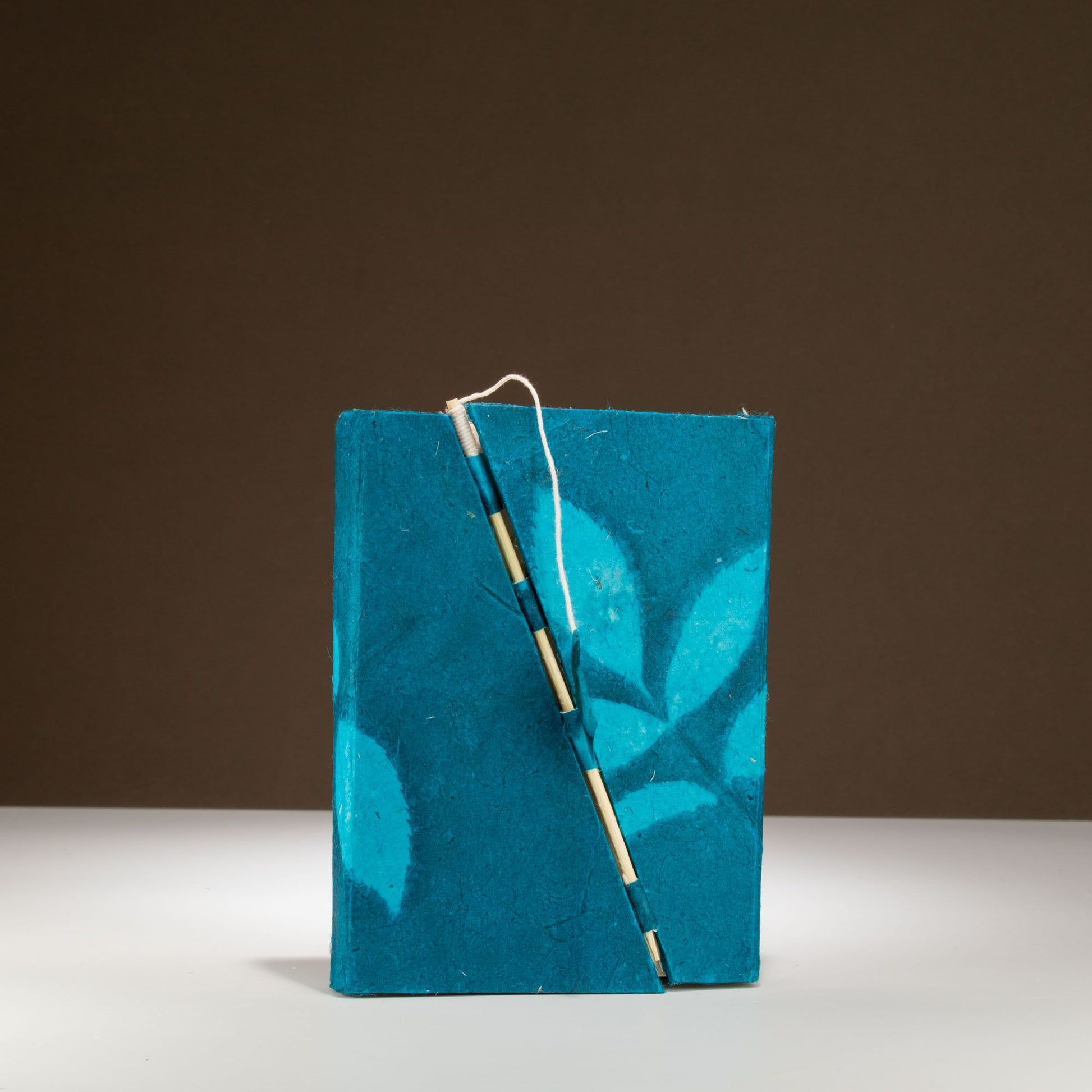 Cuaderno de papel reciclado, azul con diseño de hojas, encuadernación artesanal en color madera.