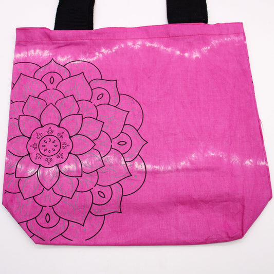 Bolsa de algodón magenta con estampado de mandala negro y efecto tie-dye. Tiene asas negras resistentes.