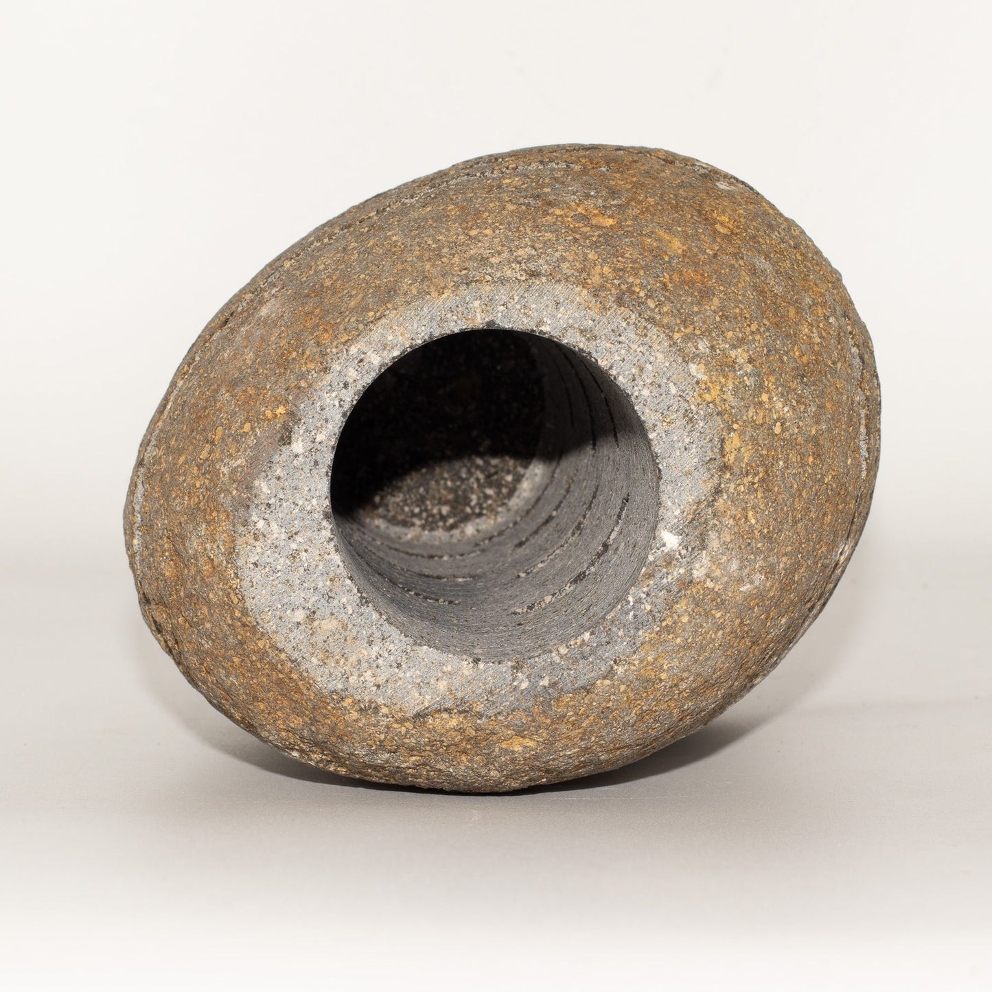 Jarrón de piedra gris y marrón, forma ovalada, acabado rústico, ideal para decoración moderna.