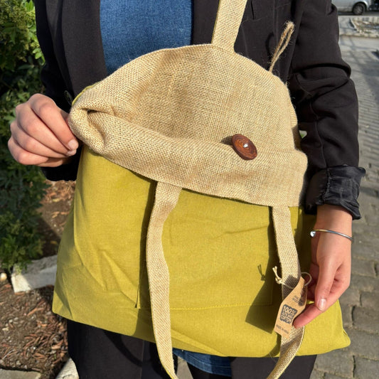 Bolsa reversible de yute natural y algodón color pistacho, con botón de madera y asas largas, colgada al hombro.