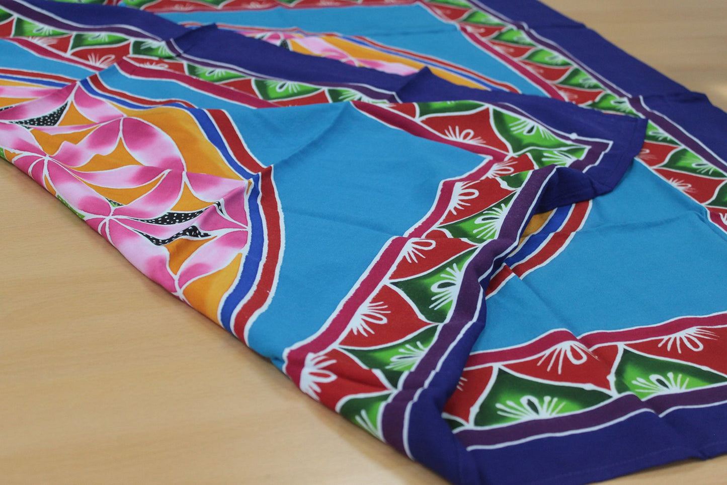 Pañuelo de seda azul con estampado de flores rosas, verdes y rojas, estilo vibrante y colorido.