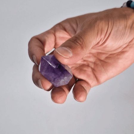 Cristal de amatista púrpura en mano, corte natural, ideal para decoración o meditación.