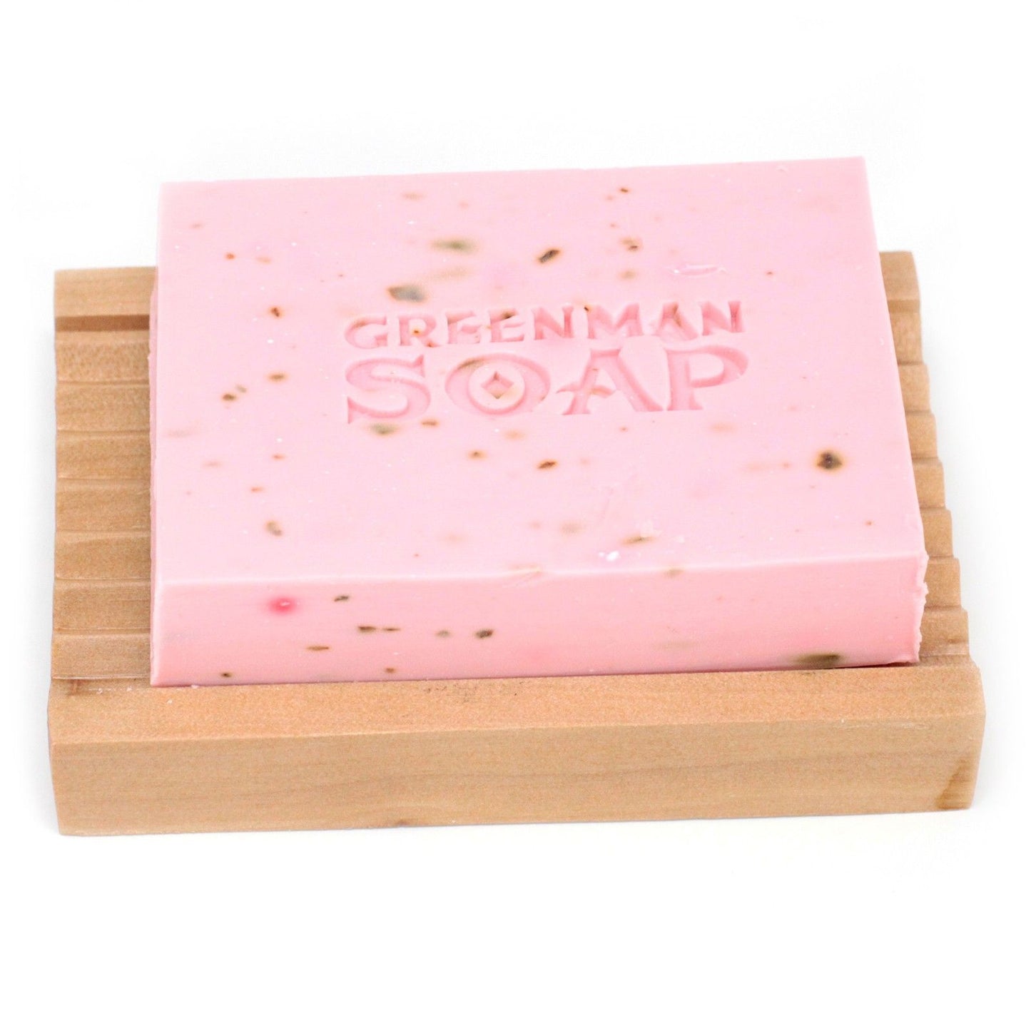 Jabón rosa con textura, grabado "GREENMAN SOAP", sobre jabonera de madera rectangular en fondo blanco.