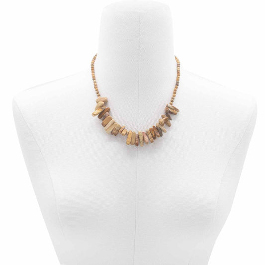 Collar de piedras naturales en tonos tierra con forma irregular, sobre busto de maniquí blanco.