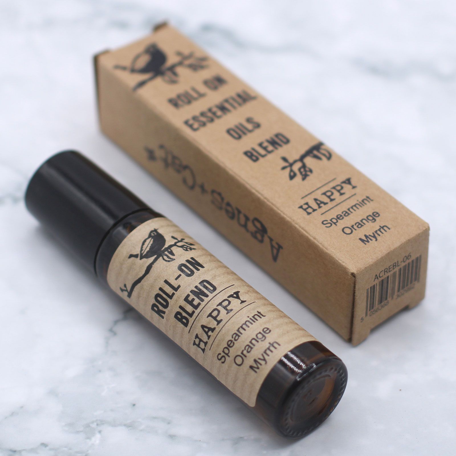 Aceite esencial roll-on "Happy" de menta, naranja y mirra, envase marrón claro con etiqueta de papel kraft.