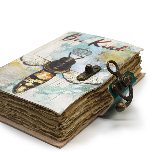 Cuaderno de cuero 18x13 cm con imagen de abeja y corona, texto "Bee Kind" y cierre de metal antiguo sobre fondo blanco.