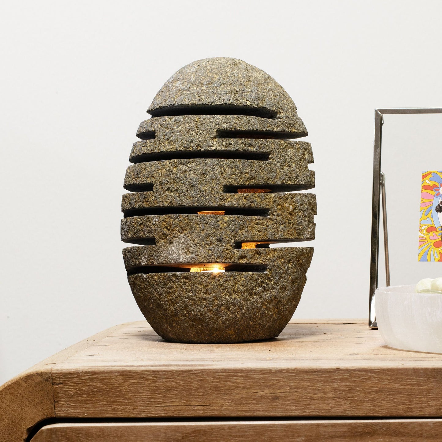 Lámpara decorativa de piedra ovalada, con ranuras negras, ideal para dar un toque rústico y moderno a tu hogar.