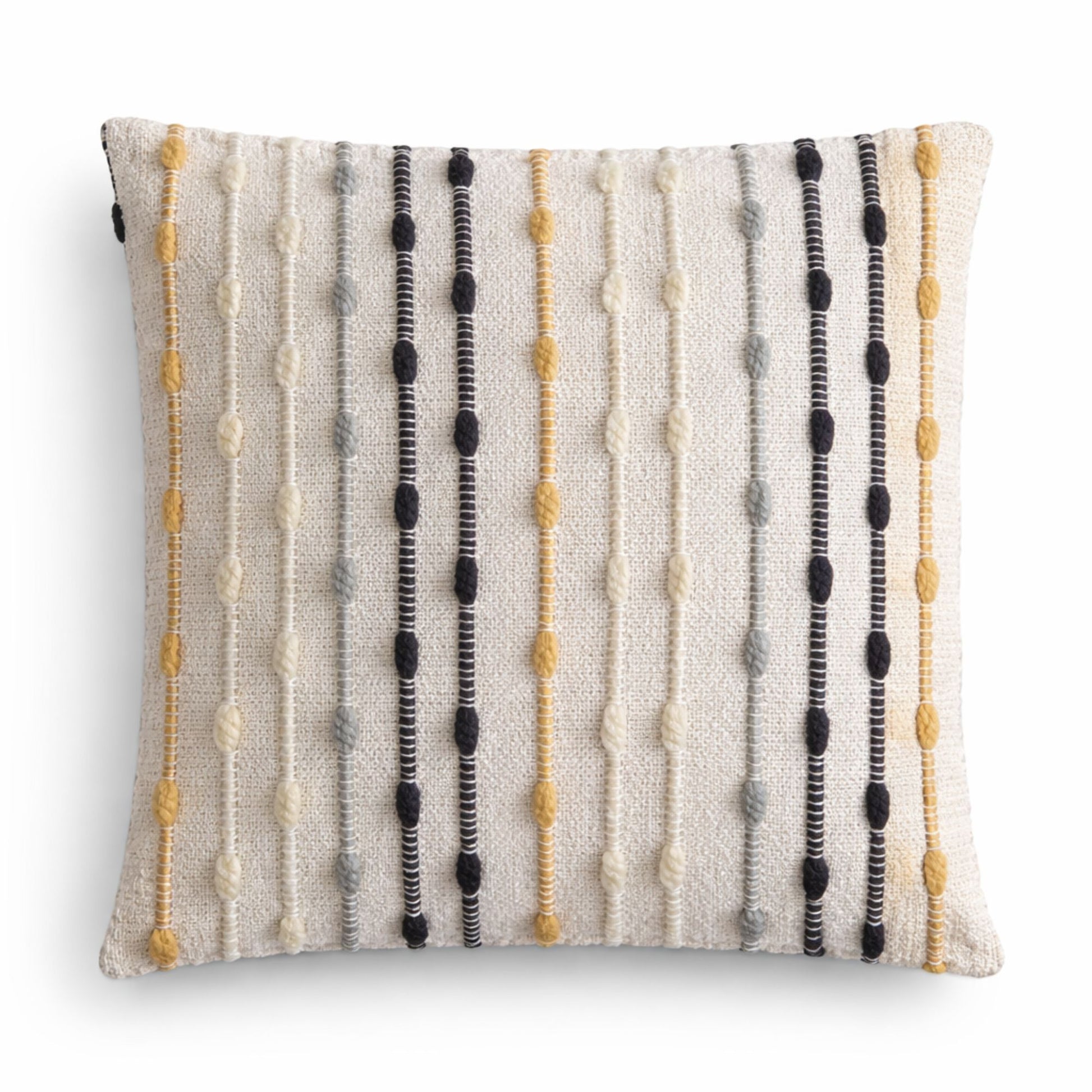 Cojín decorativo en tonos beige, negro y amarillo, con textura de rayas en materiales suaves y modernos.