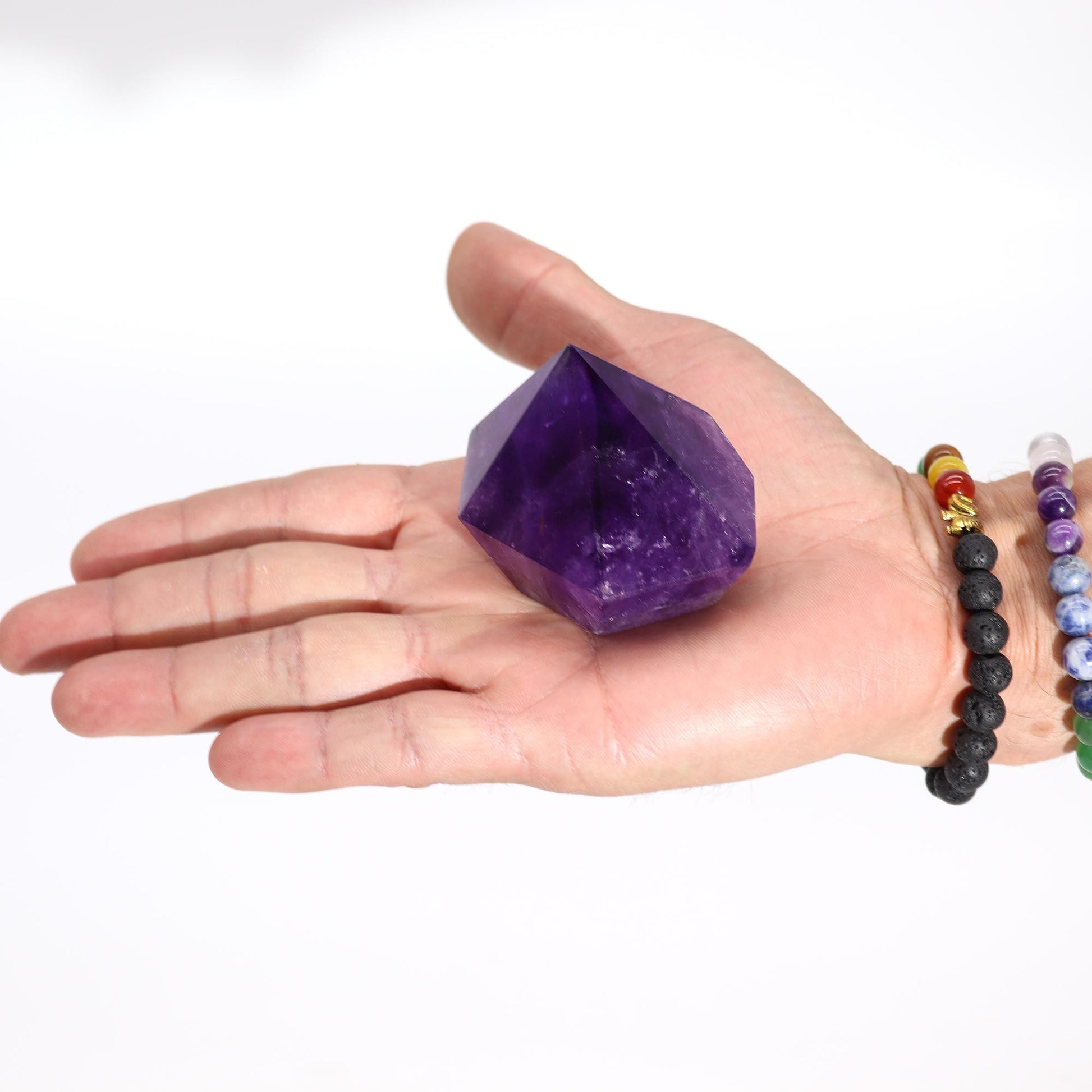 Cristal de amatista púrpura en forma de pirámide, sostenido en una mano. Ideal para decoración y energías positivas.