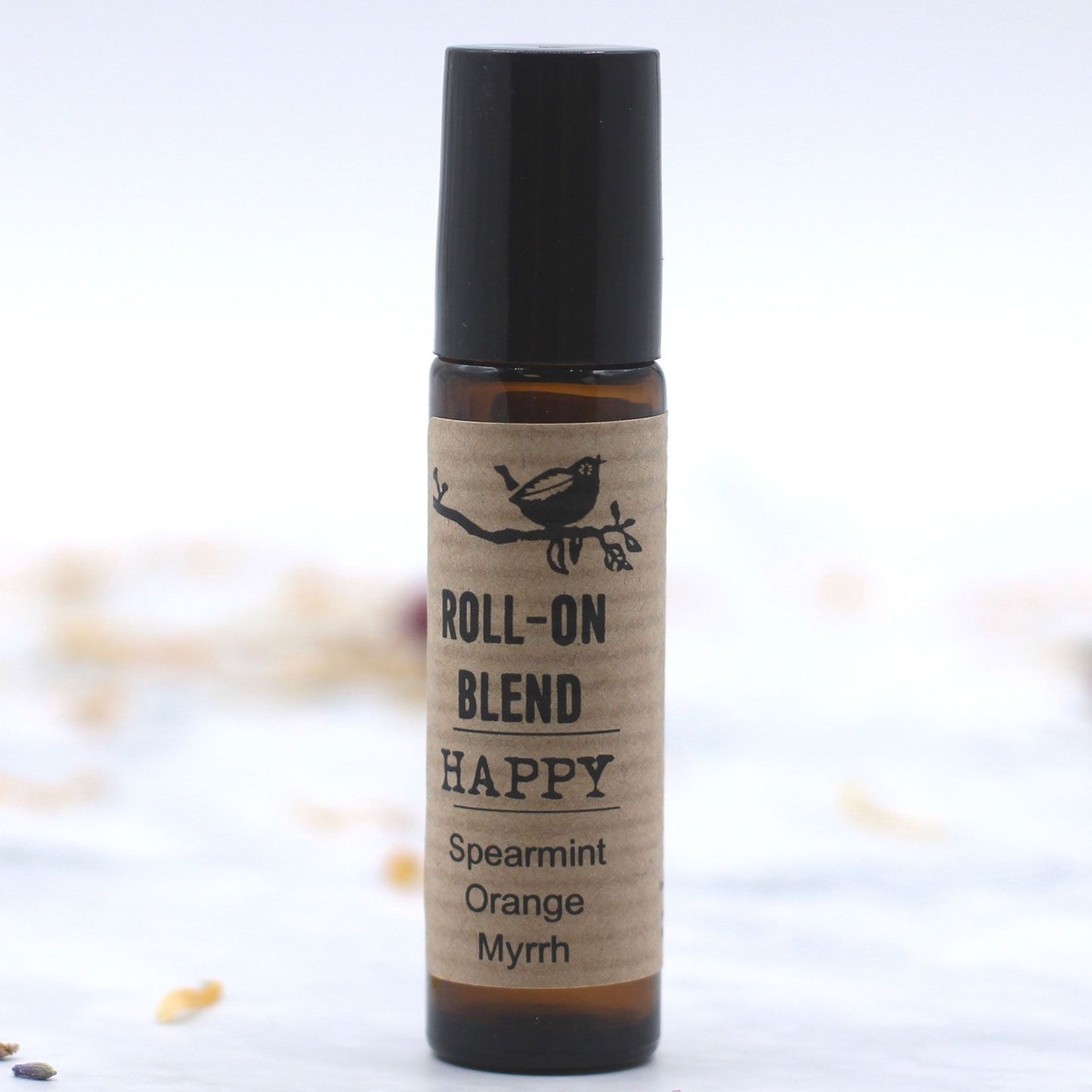 Aceite esencial roll-on Happy de menta, naranja y mirra, en frasco marrón con tapa negra.