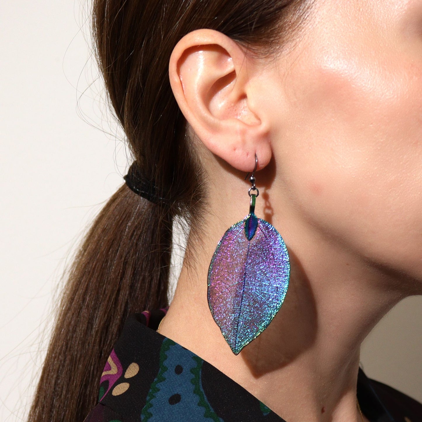 Pendientes grandes de hoja en tonos iridiscentes, elaborados en acrílico. Estilo moderno y llamativo.