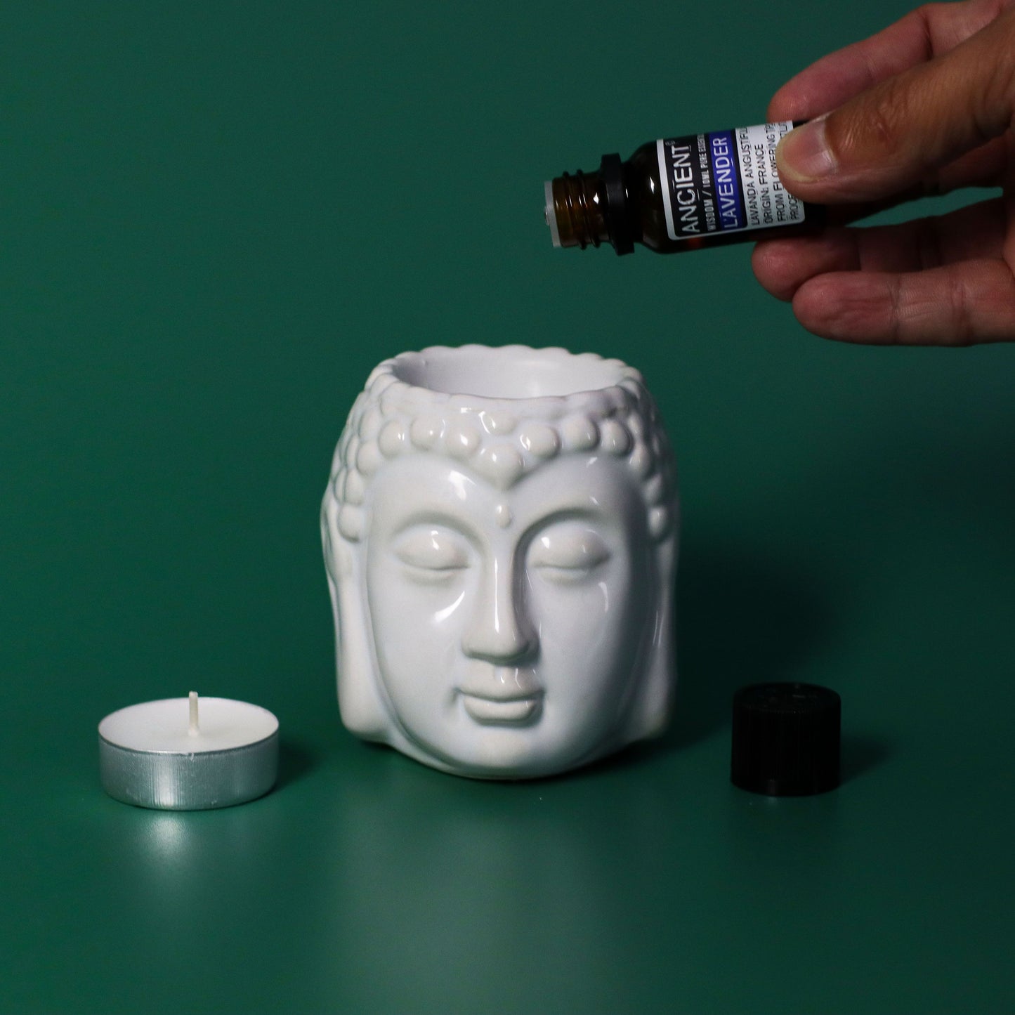 Portavelas de cerámica blanca en forma de Buda, con aceites esenciales y vela blanca. Ideal para decoración y aromaterapia.