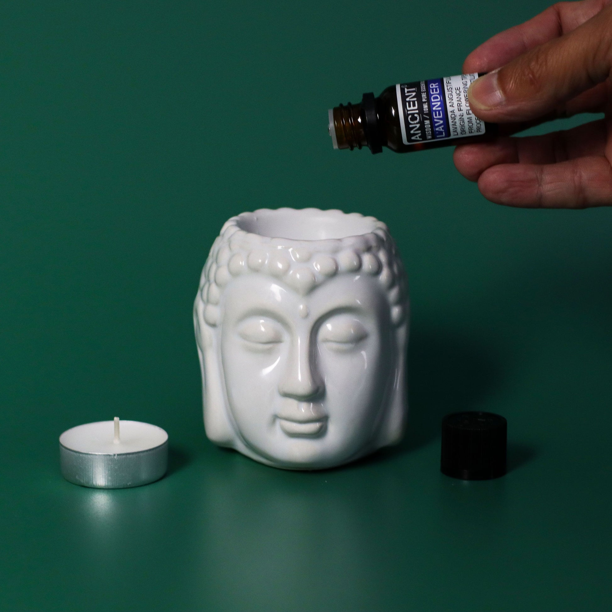 Portavelas de cerámica blanca en forma de Buda, con aceites esenciales y vela blanca. Ideal para decoración y aromaterapia.
