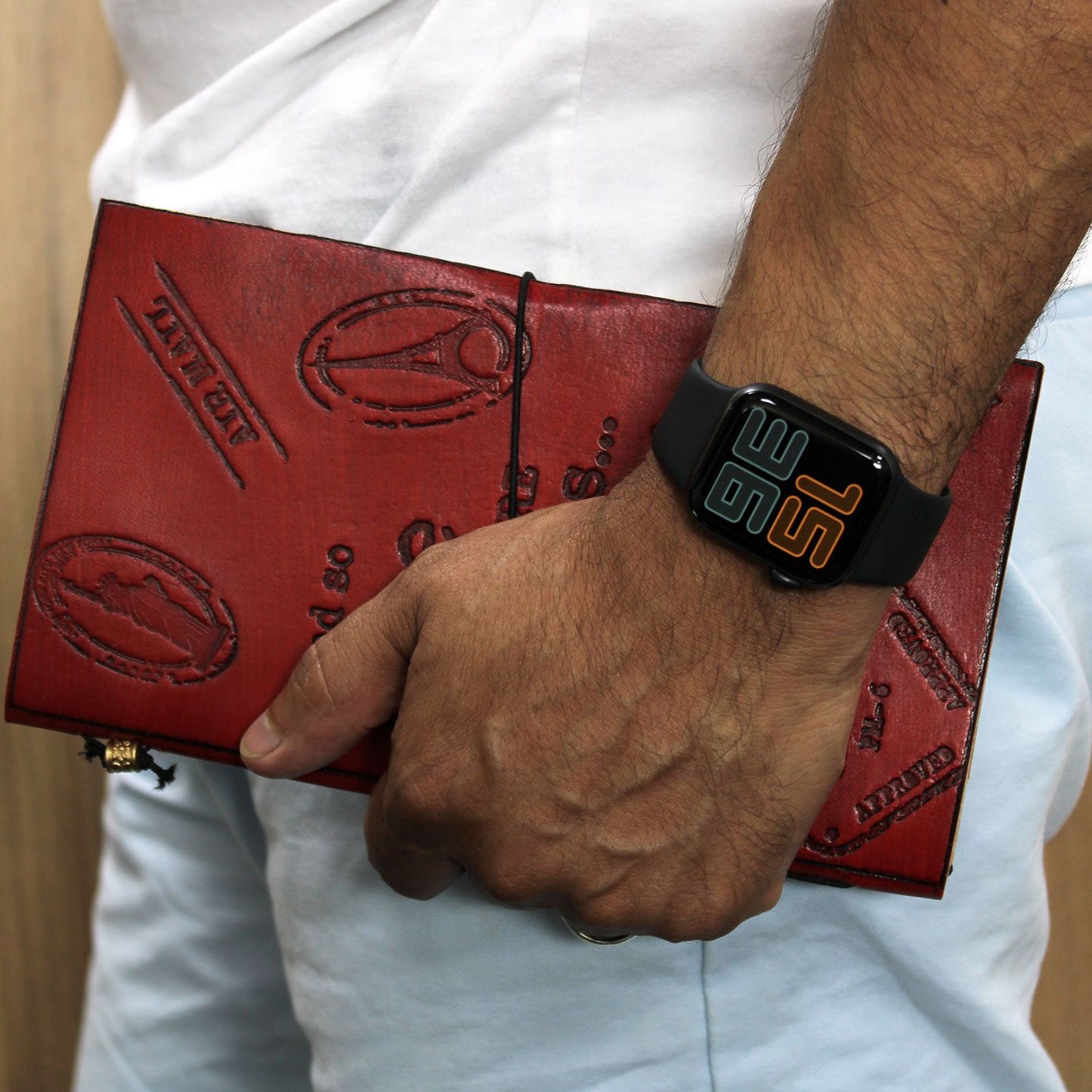 Reloj smartwatch negro con detalles naranjas y pulsera de cuero rojo con estampado, estilo moderno y práctico.