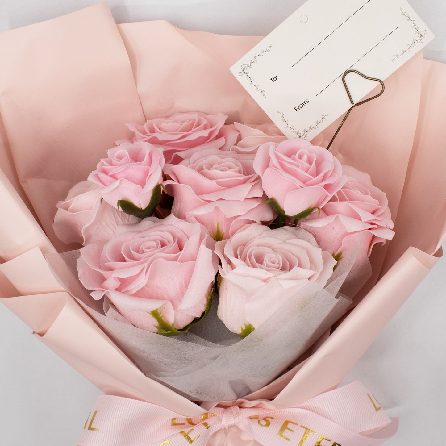 Ramo de rosas rosas con papel de regalo suave y cintilla, perfecto para ocasiones especiales.