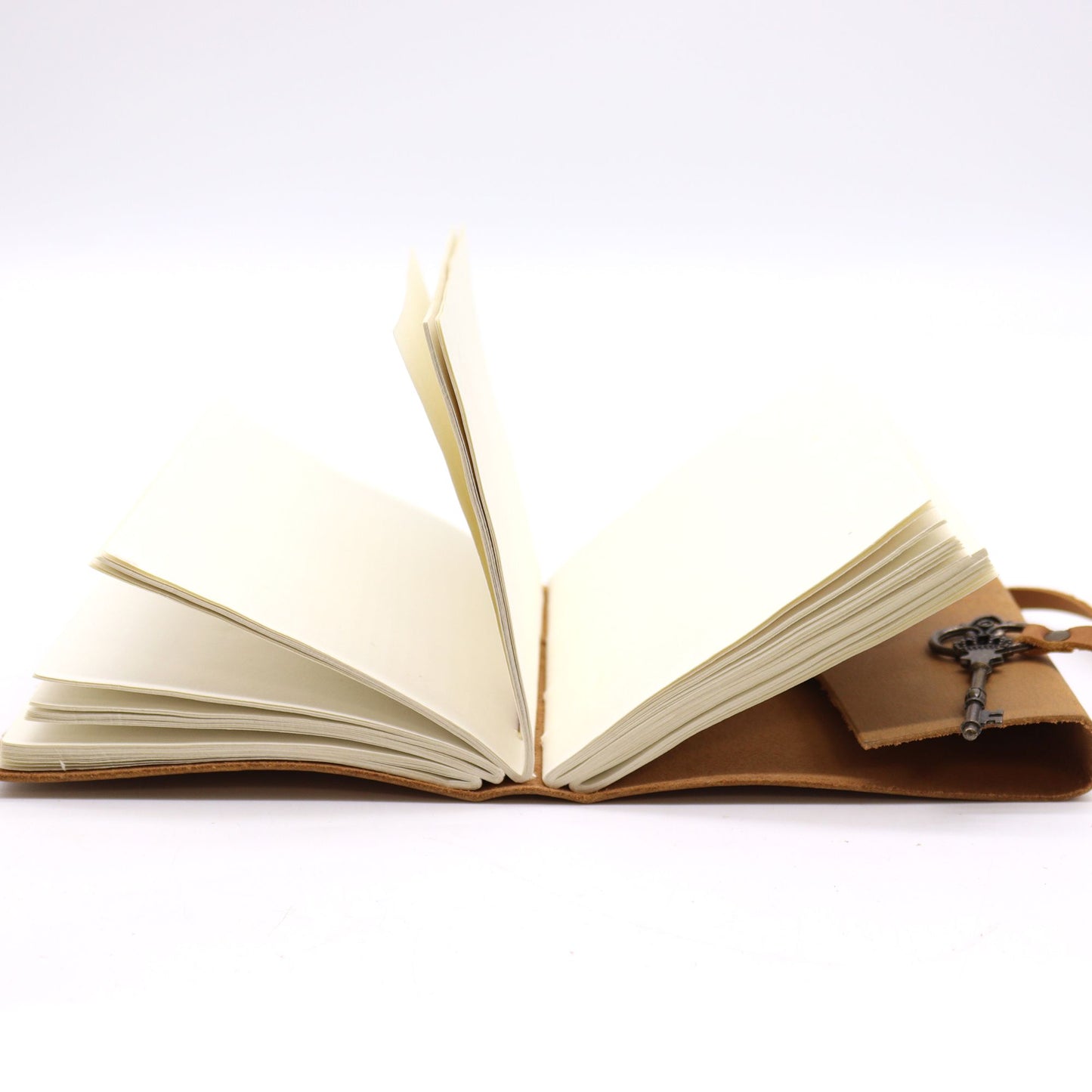 Cuaderno de cuero marrón con llavero, hojas en blanco, estilo vintage para notas y diario personal.