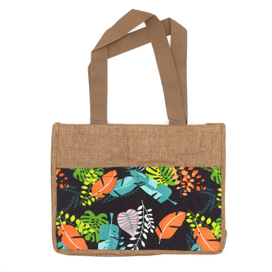 Bolsa de yute con asas marrones y bolsillo frontal de tela negra con estampado de hojas tropicales coloridas.