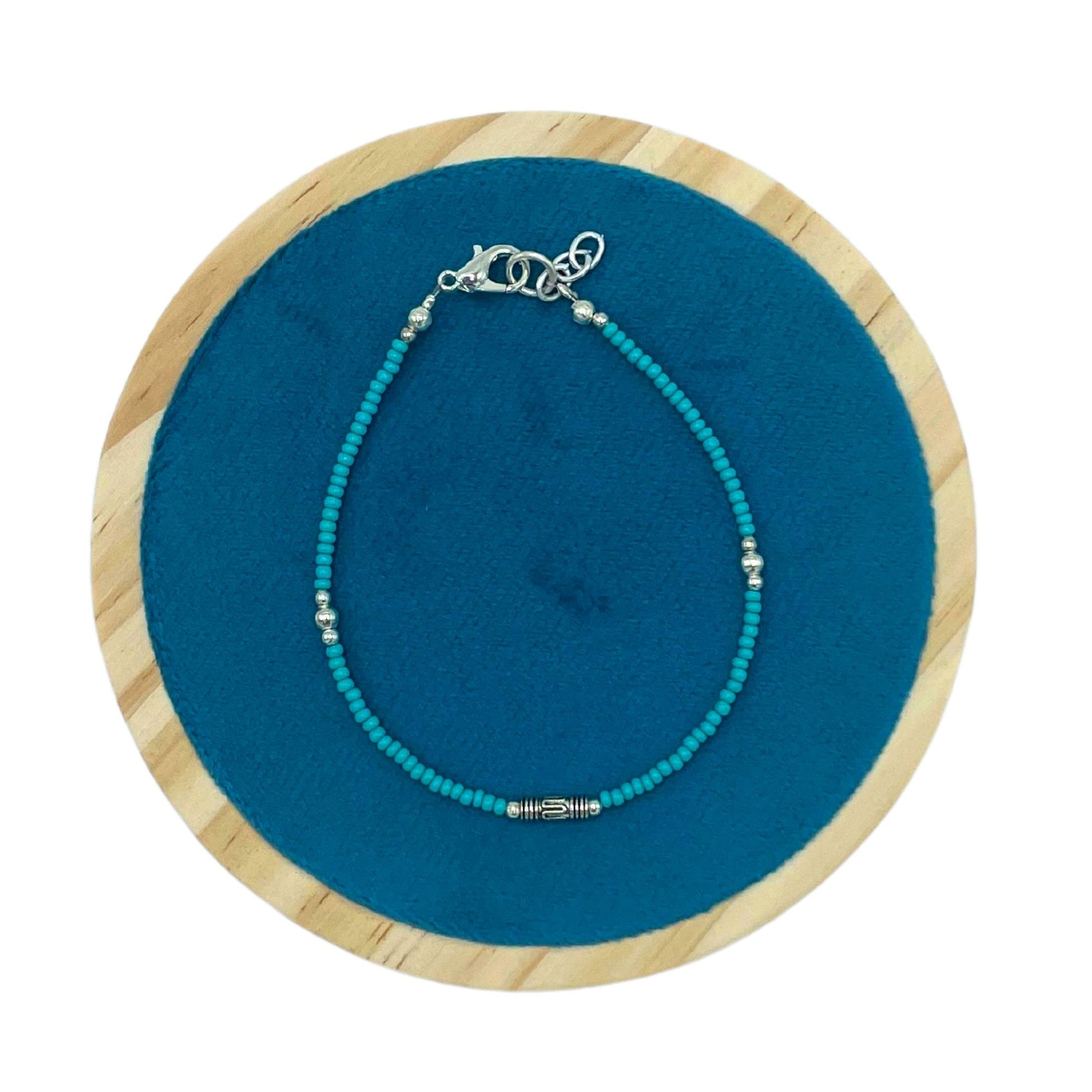 Collar de cuentas turquesas con detalles plateados, estilo bohemio, sobre fondo azul.