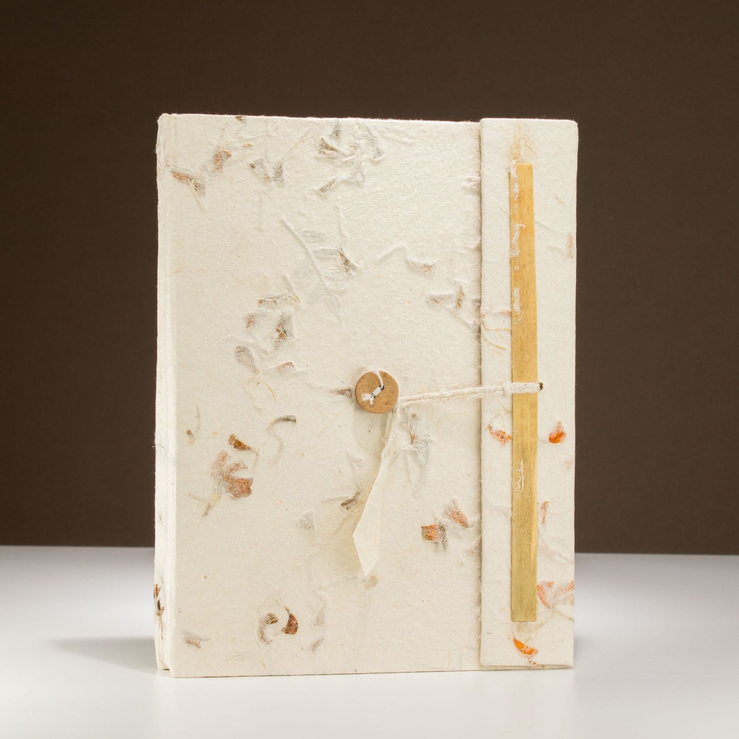 Cuaderno artesanal color blanco, hecho de papel reciclado, con detalles en relieve y cierre de madera.