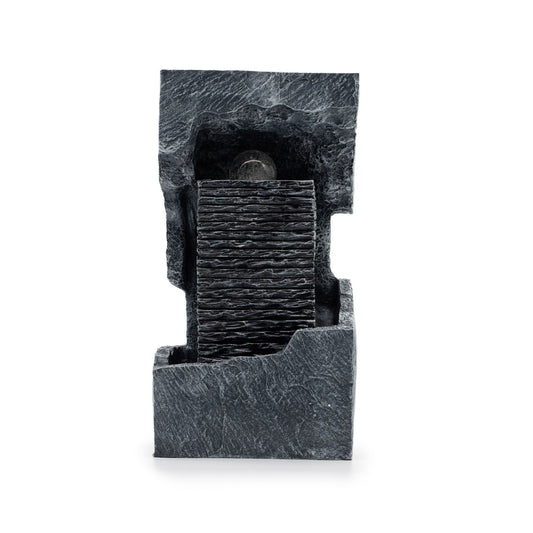 Fuente decorativa de piedra negra con capas texturizadas y detalles en gris, ideal para interiores modernos.