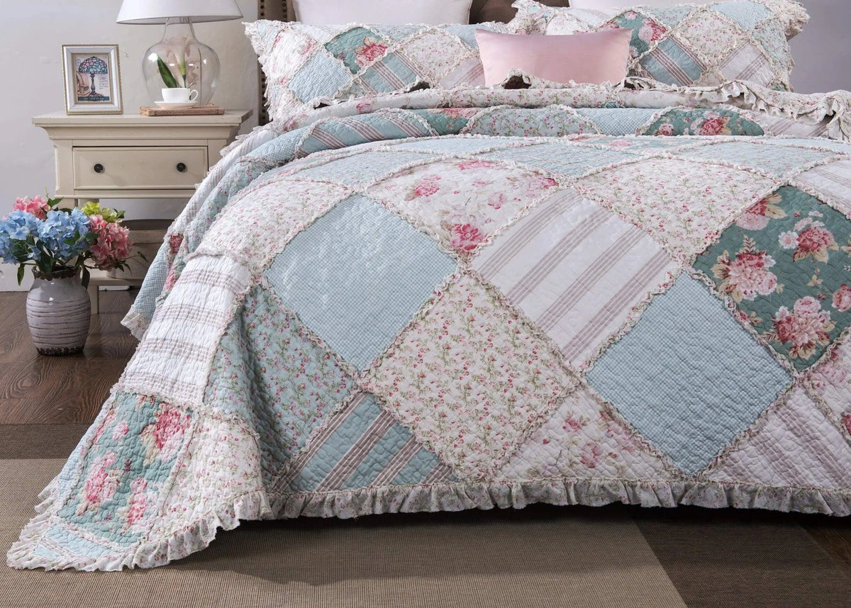 Vintage floral patched quilt set in soft blue, pink, and white, featuring ruffle edges and coordinating pillow shams.