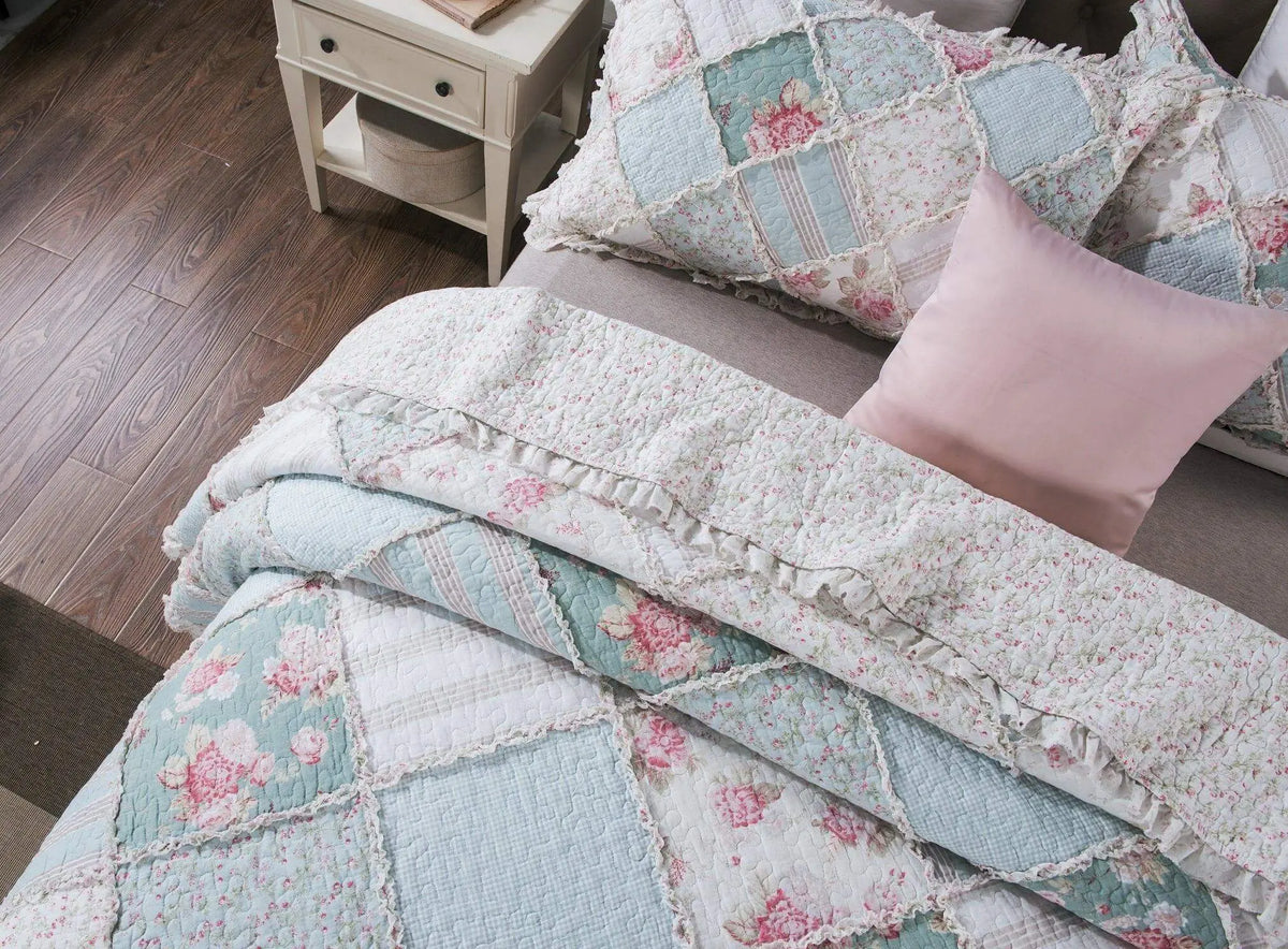 Vintage floral patchwork quilt set in pastel pink and blue, featuring ruffled edges, perfect for cozy bedrooms.