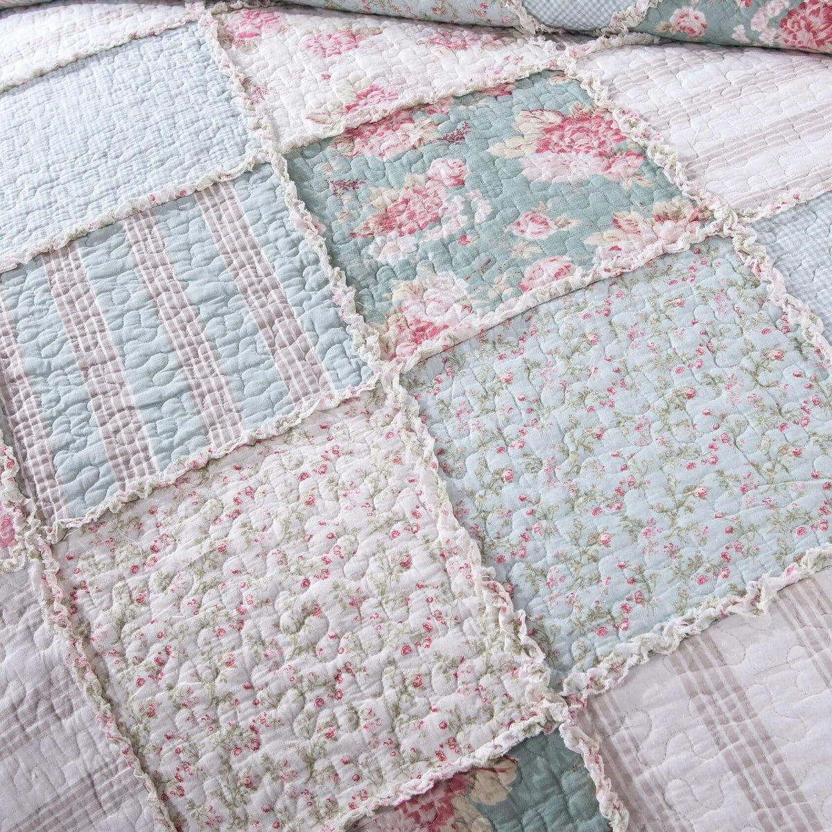 Quilted patchwork quilt in pastel blue, pink, and white floral patterns with frill trim, perfect for vintage decor.
