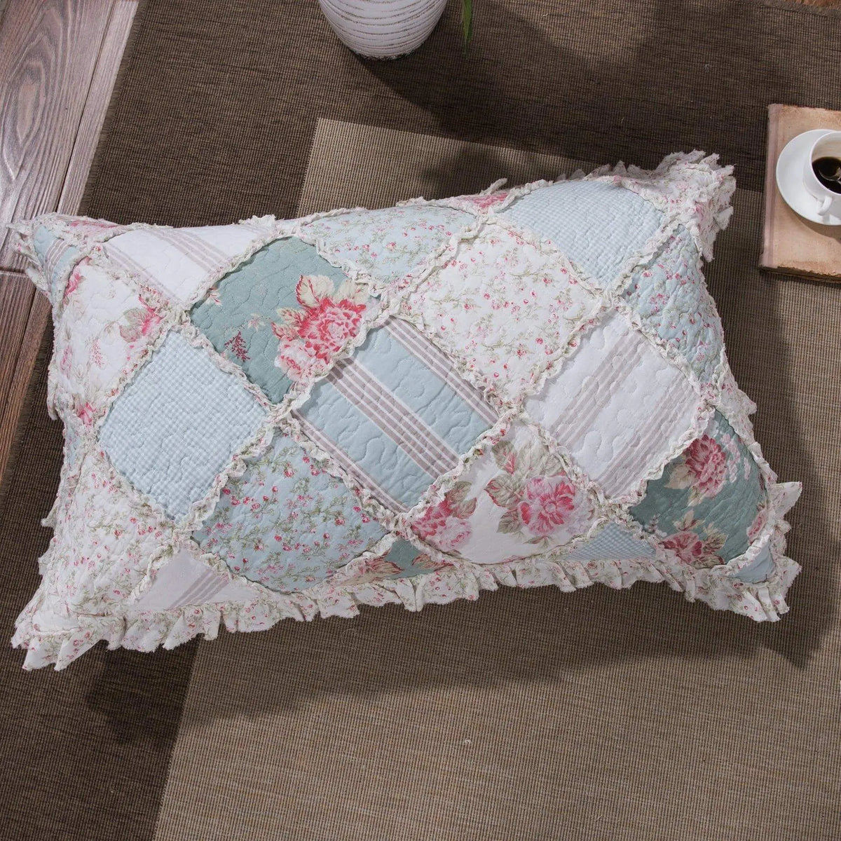 Vintage floral patchwork pillow in pastel blue and pink with lace trim, perfect for cozy home decor.