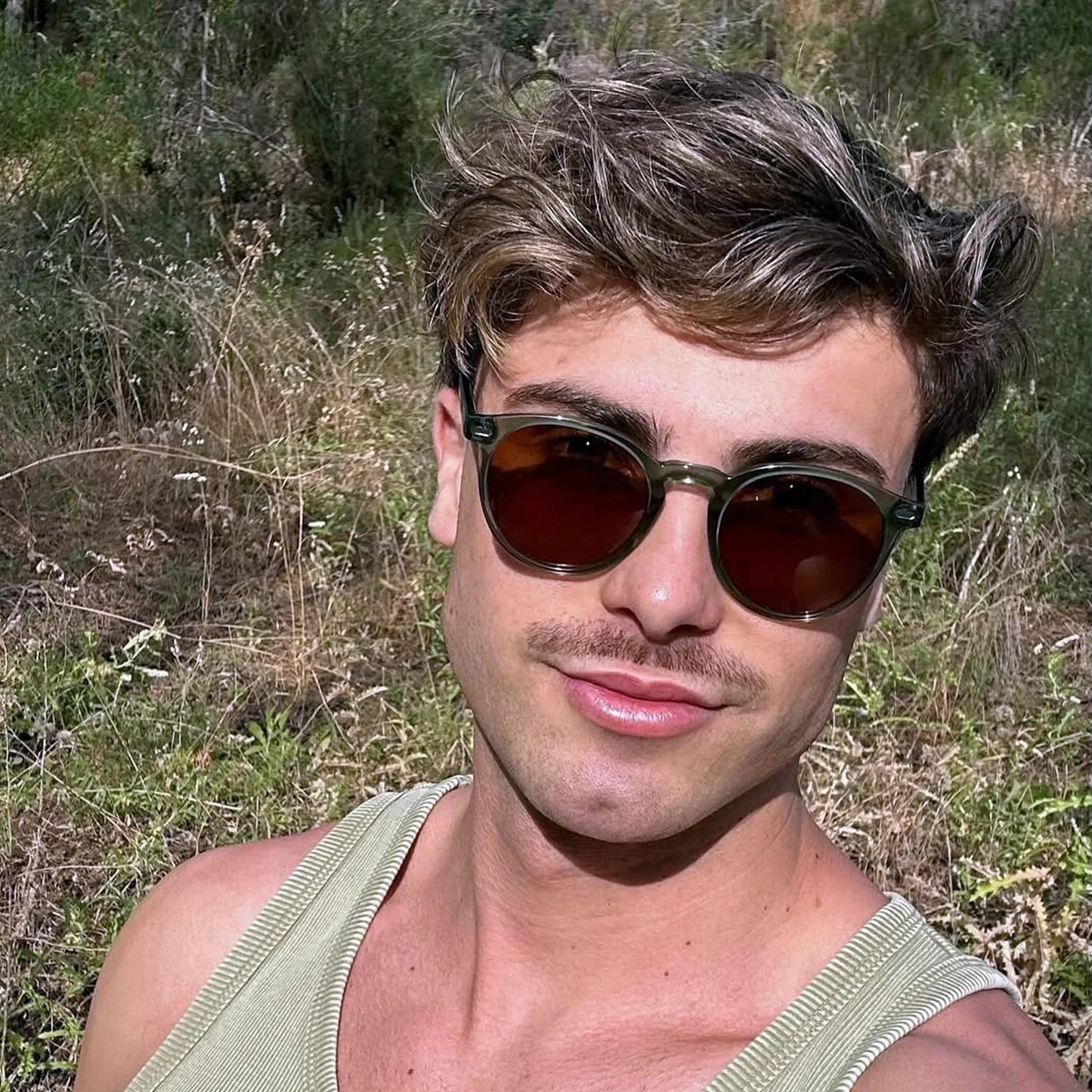 Bolonia · gafas de sol redondas de cristal verde con lentes marrones. Modelo masculino en escena