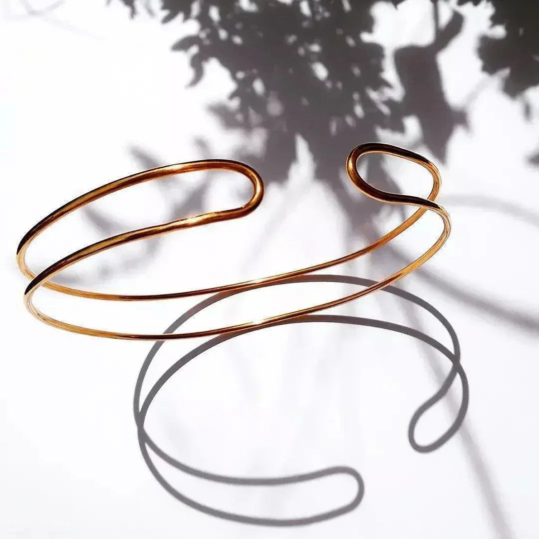 Pulsera abierta de acero dorado con diseño minimalista y elegante, ideal para cualquier ocasión.