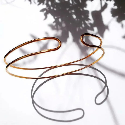 Pulsera abierta de acero dorado con diseño minimalista y elegante, ideal para cualquier ocasión.