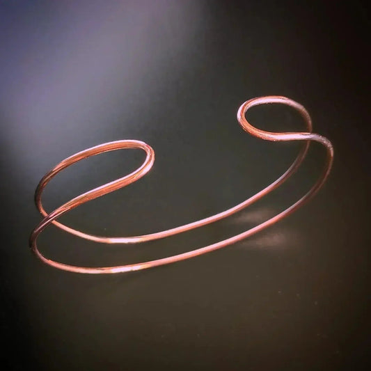 Pulsera de cobre rosa, diseño minimalista y moderno, con dos bucles elegantes y abiertos.