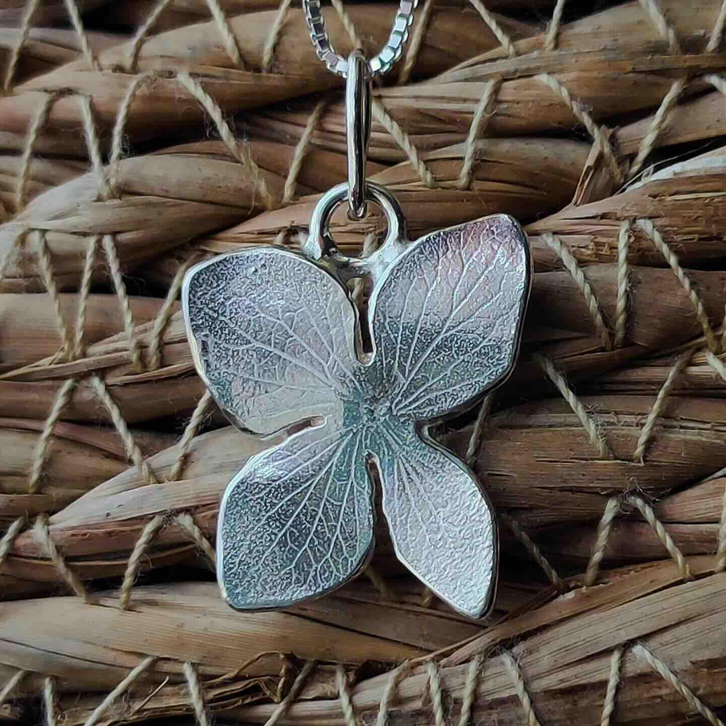Colgante de mariposa de plata esterlina, acabado brillante, con detalles texturizados. Ideal para estilo elegante.