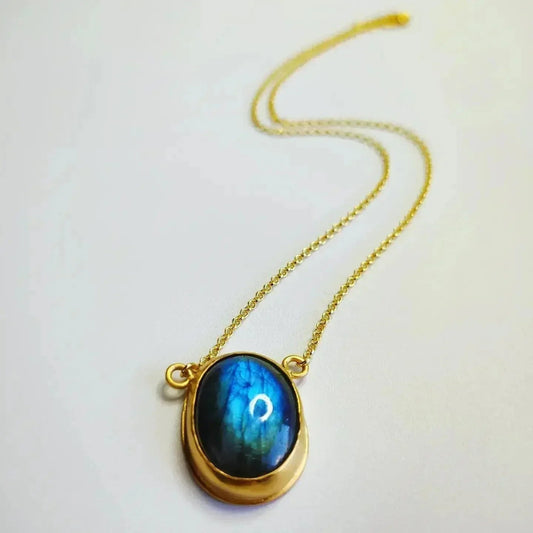 Collar dorado con piedra labradorita azul en forma ovalada y cadena delicada.