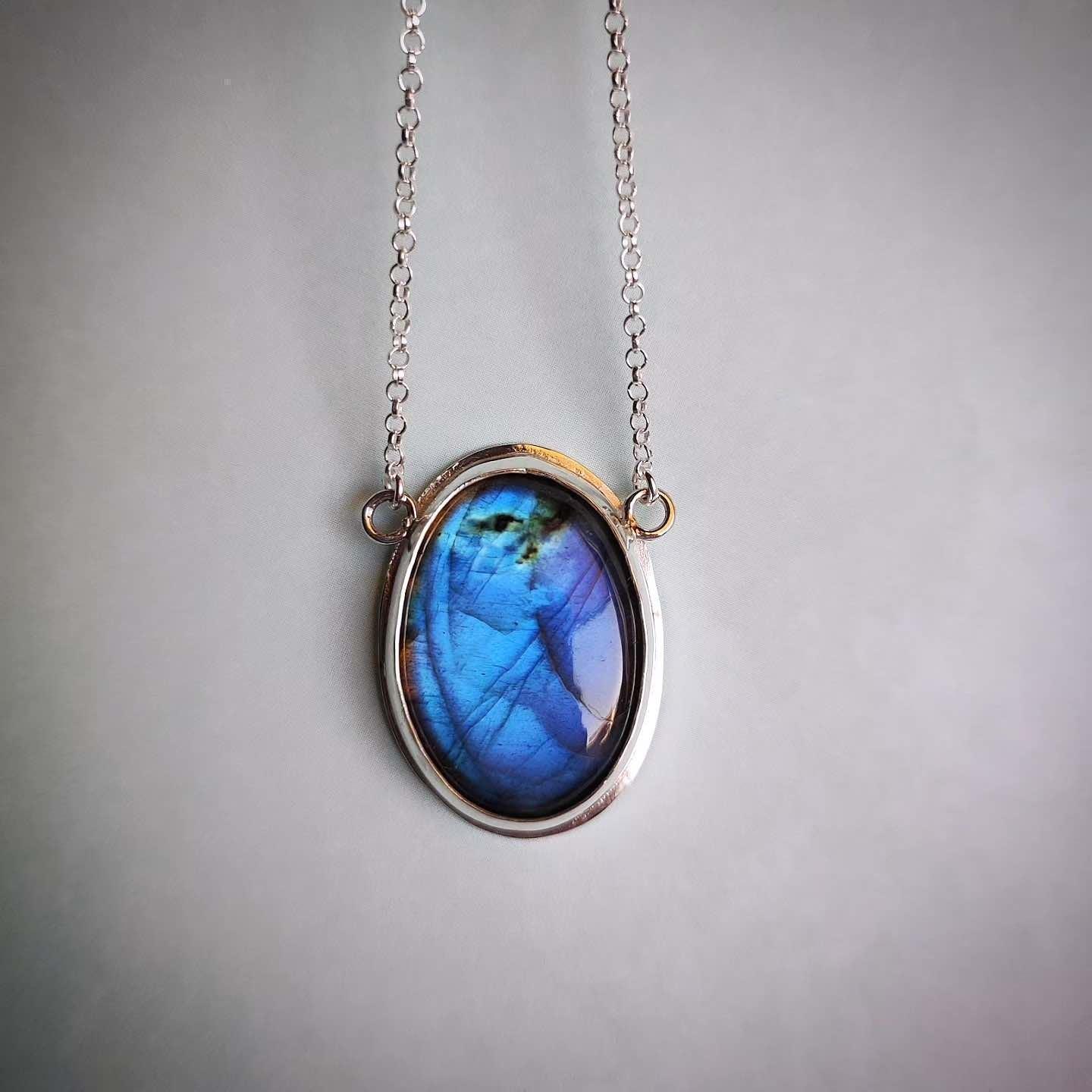 Collar de plata con pendant ovalado de labradorita azul y dorado, estilo moderno y elegante.