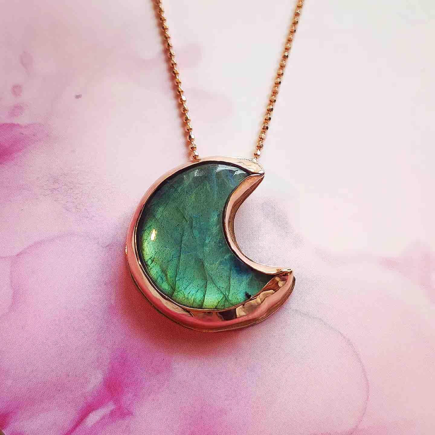 Collar con colgante en forma de luna, color verde y dorado, hecho de resina y metal. Ideal para un look moderno.