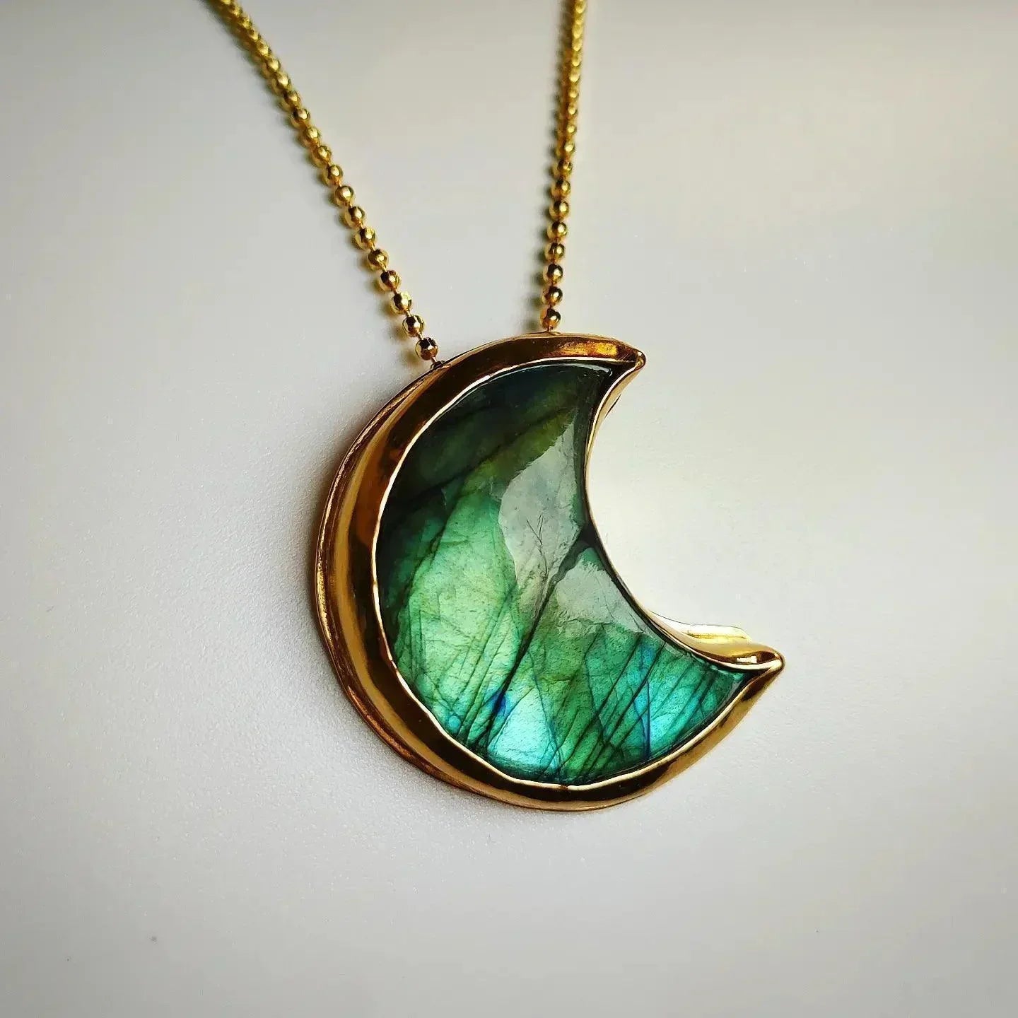 Collar con colgante de luna en labradorita verde y dorado, estilo bohemio y elegante.