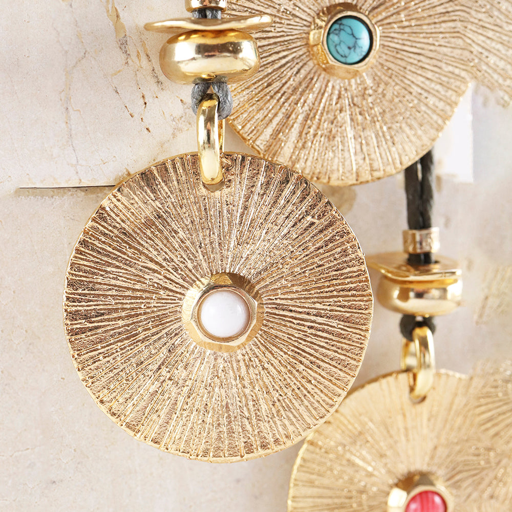 Collar moderne de metal dorado con detalles en turquesa y coral, diseño circular texturizado y cierre de botón.