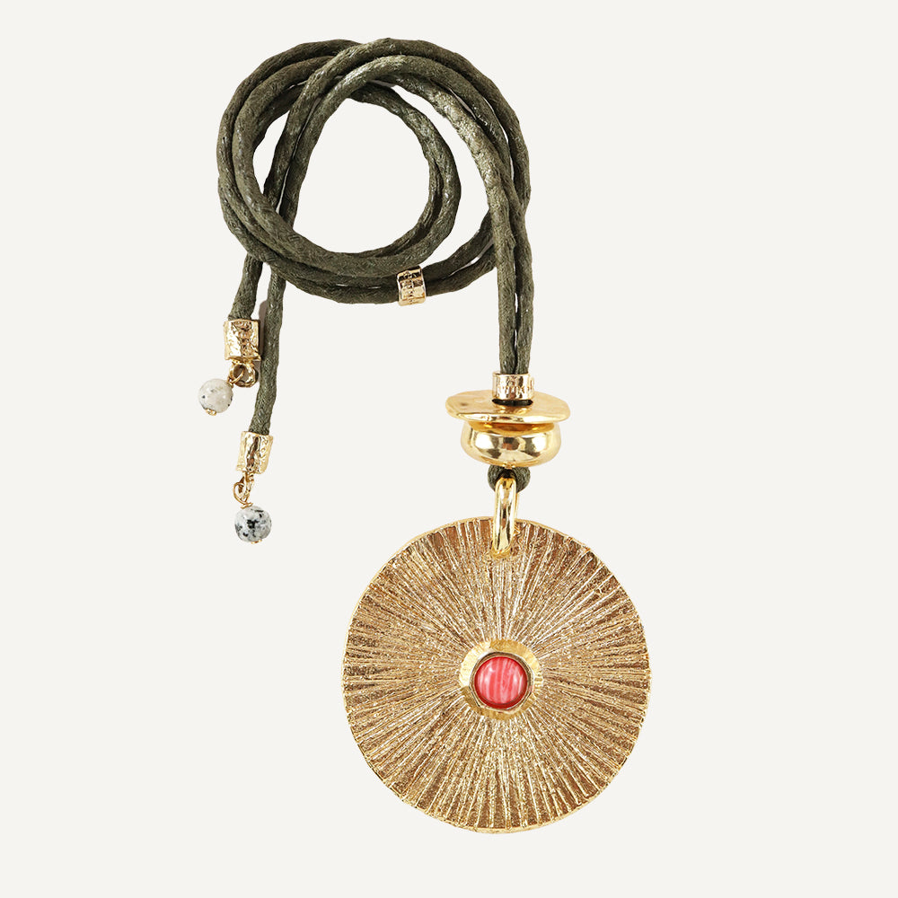 Collar de estilo bohemio con medallón dorado y piedra roja, cordón verde y detalles en piedras.