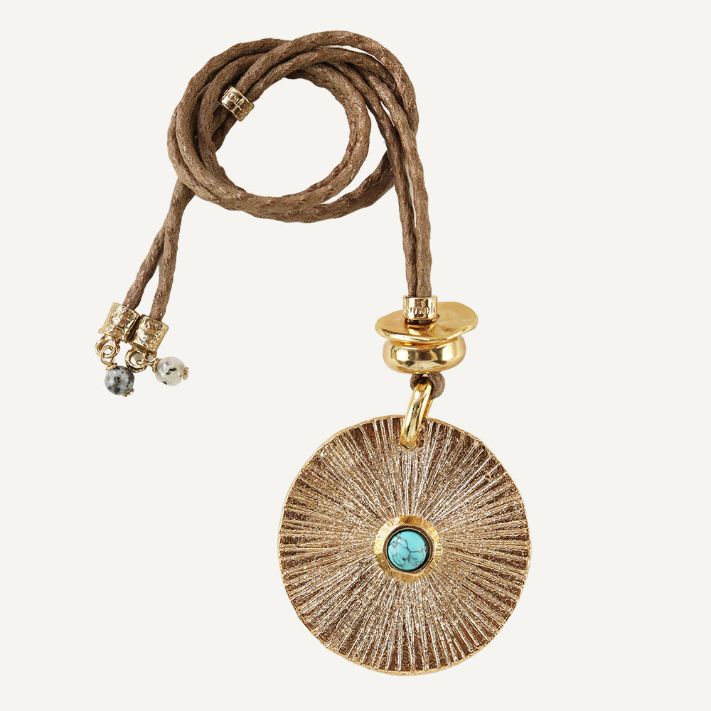 Collar de metal dorado con colgante circular y turquesa, cordón trenzado en color marrón. Estilo bohemio.