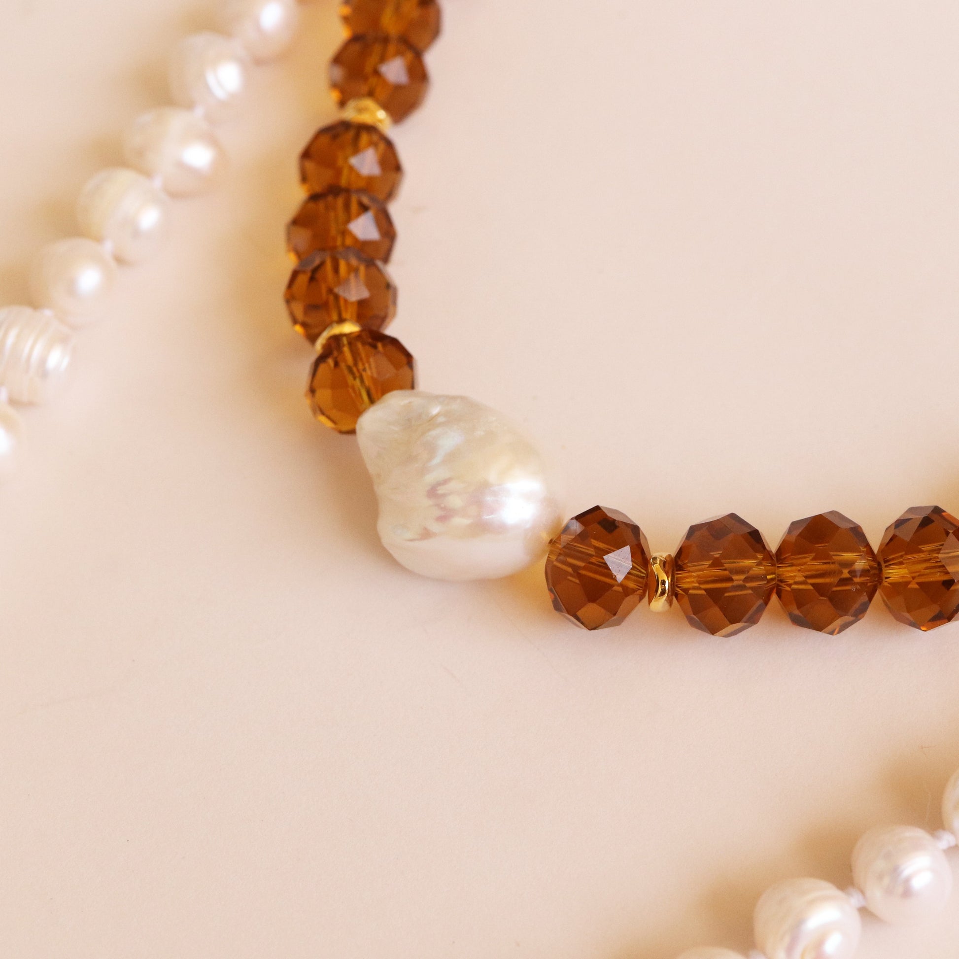 Collar de perlas blancas y ámbar facetado, con una perla irregular en el centro, elegante y artesanal.