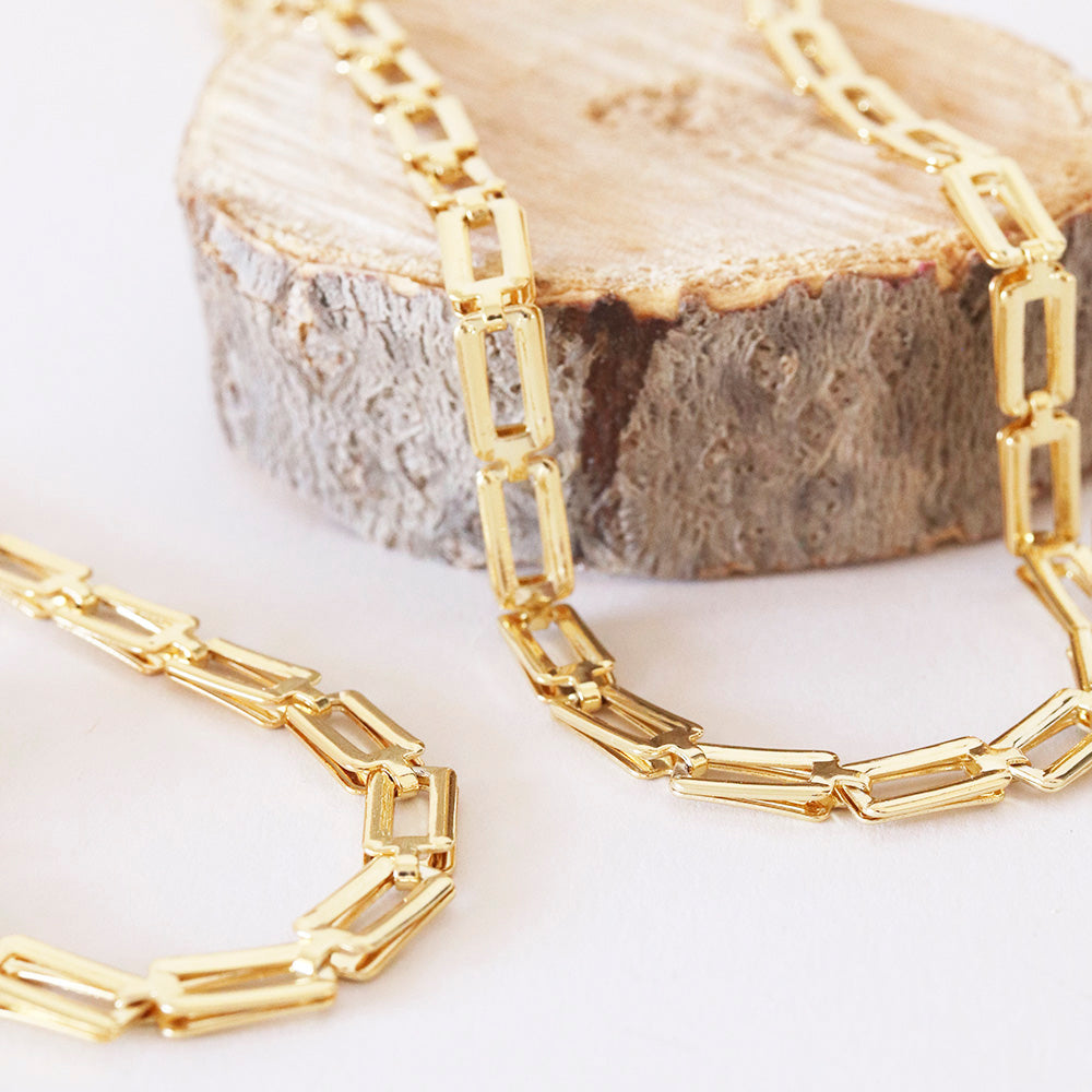Collar de eslabones dorados, estilo moderno, elaborado en acero inoxidable, sobre fondo de madera clara.
