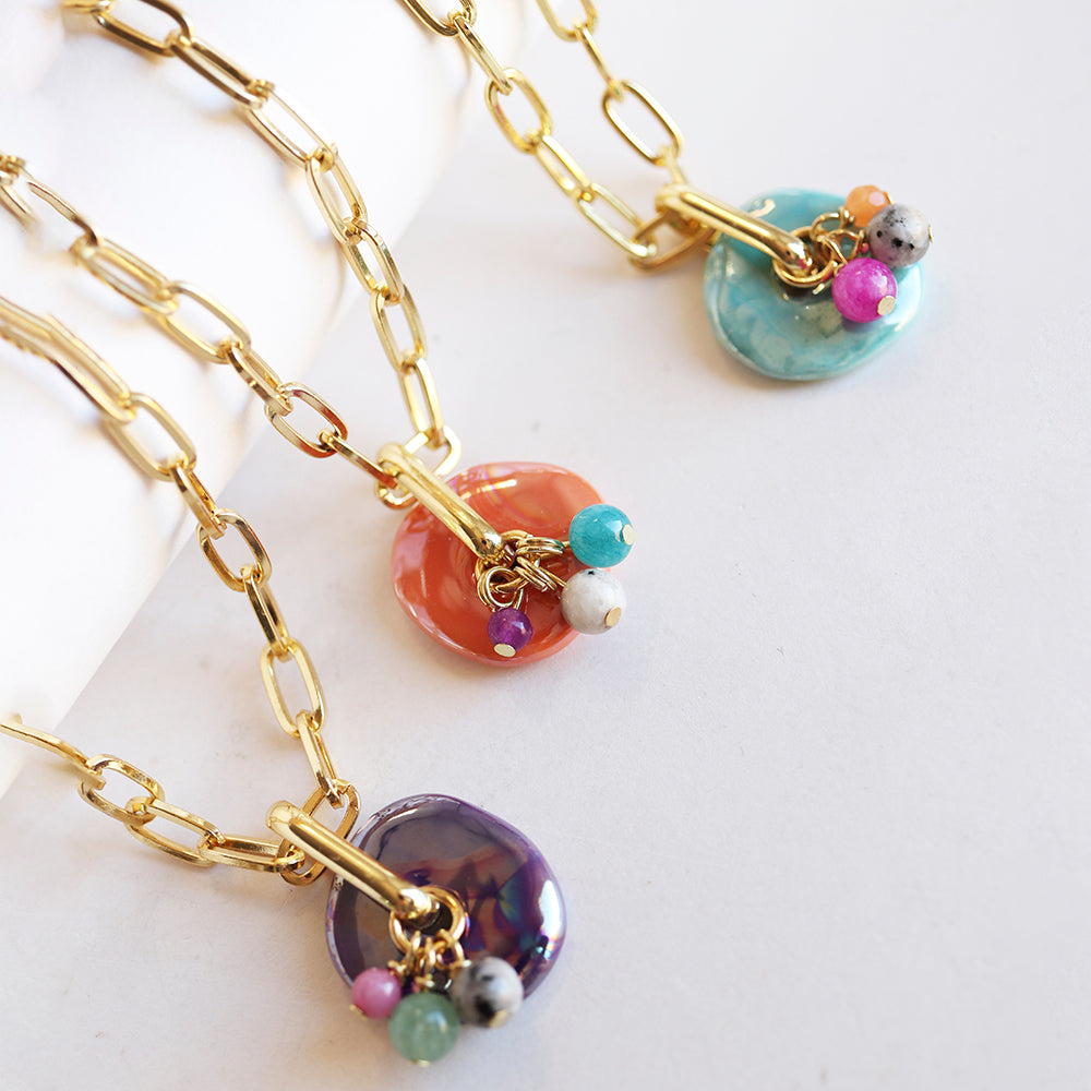 Collares de eslabones dorados con colgantes de cerámica en tonos coral, azul y púrpura, decorados con cuentas de colores.