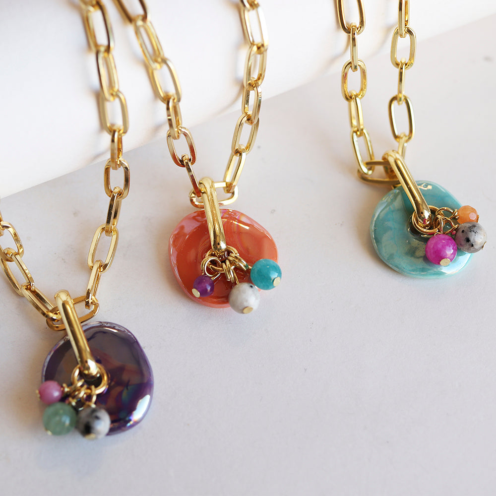Collares de cadena dorada con colgantes de cerámica en tonos púrpura, naranja y azul, decorados con piedras de colores.